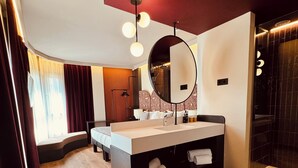 Un baño moderno con un espejo grande, tocador con lavamanos y zona de ducha.