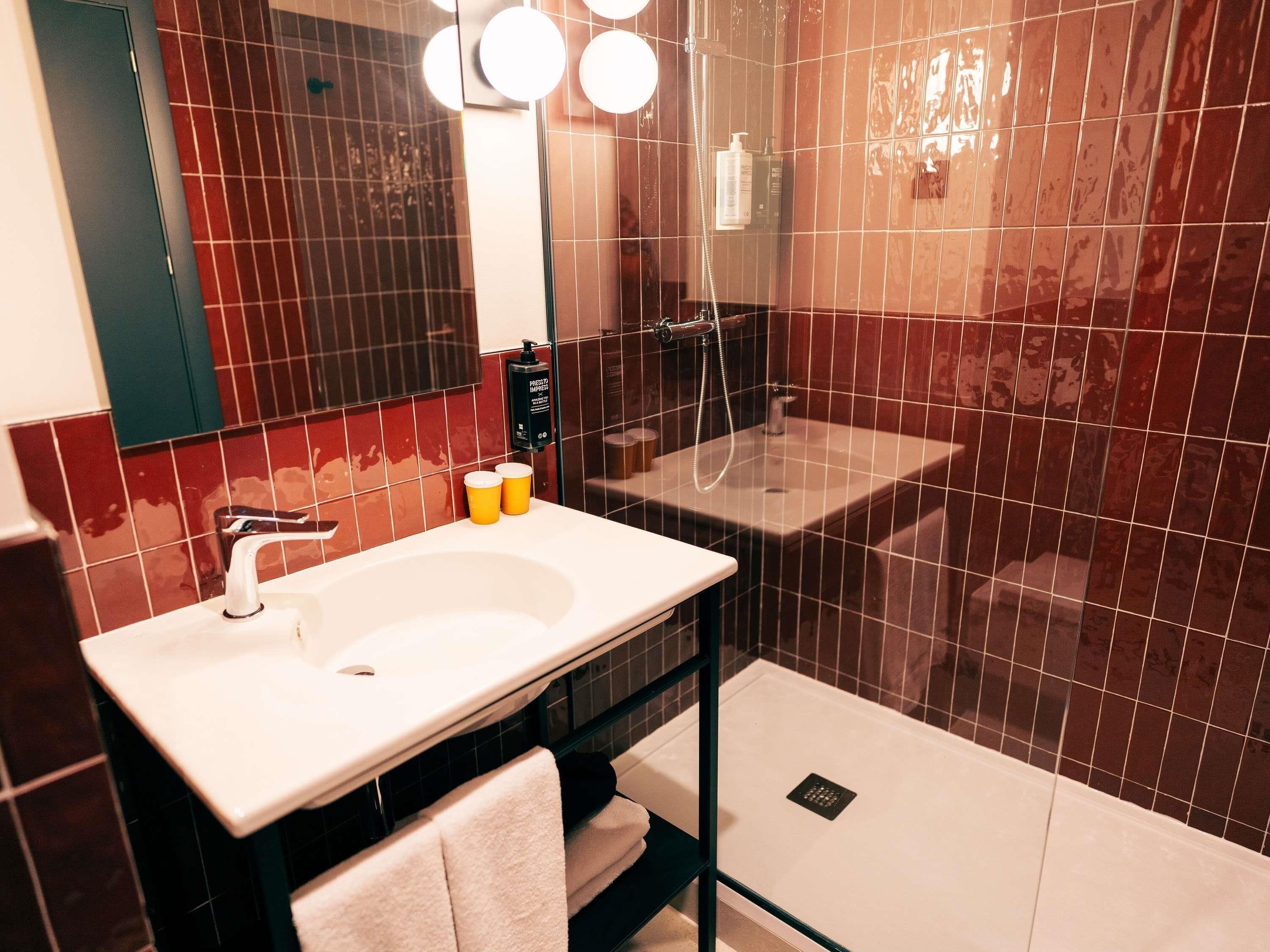 A modern bathroom with a white sink, a mirror, and a glass-enclosed shower area.