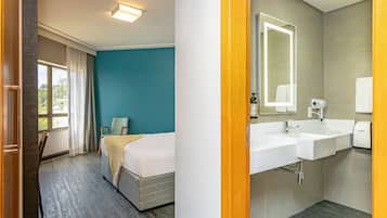 Una habitación de hotel con una cama, una silla, un espejo grande, un lavabo y una ventana con cortinas.