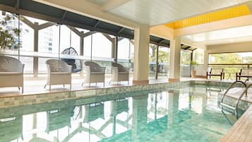 Una piscina techada, sillones reclinables de piscina