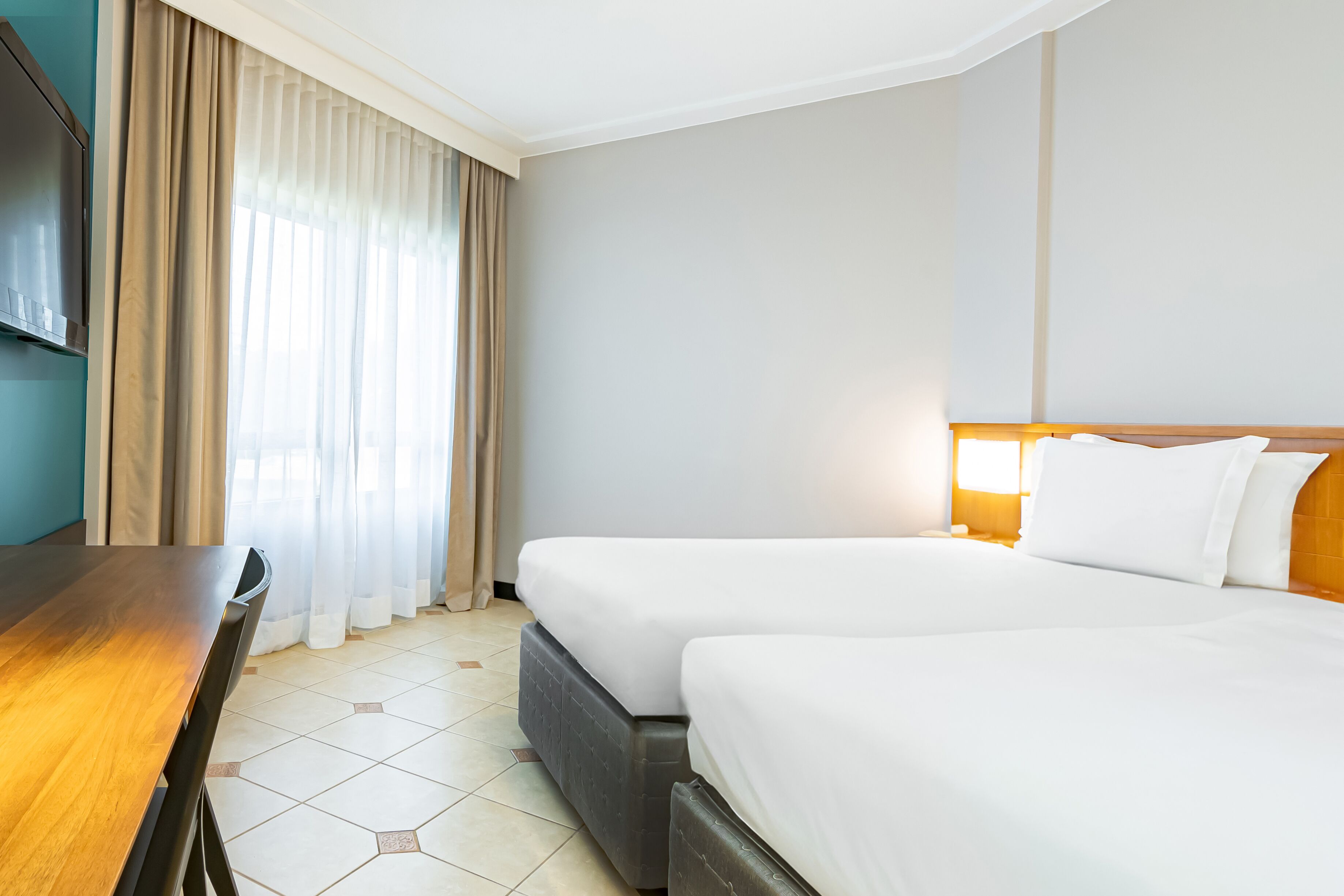 Una habitación de hotel con cama, mesita de noche y televisión.