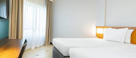 Una habitación de hotel con cama, mesita de noche y televisión.