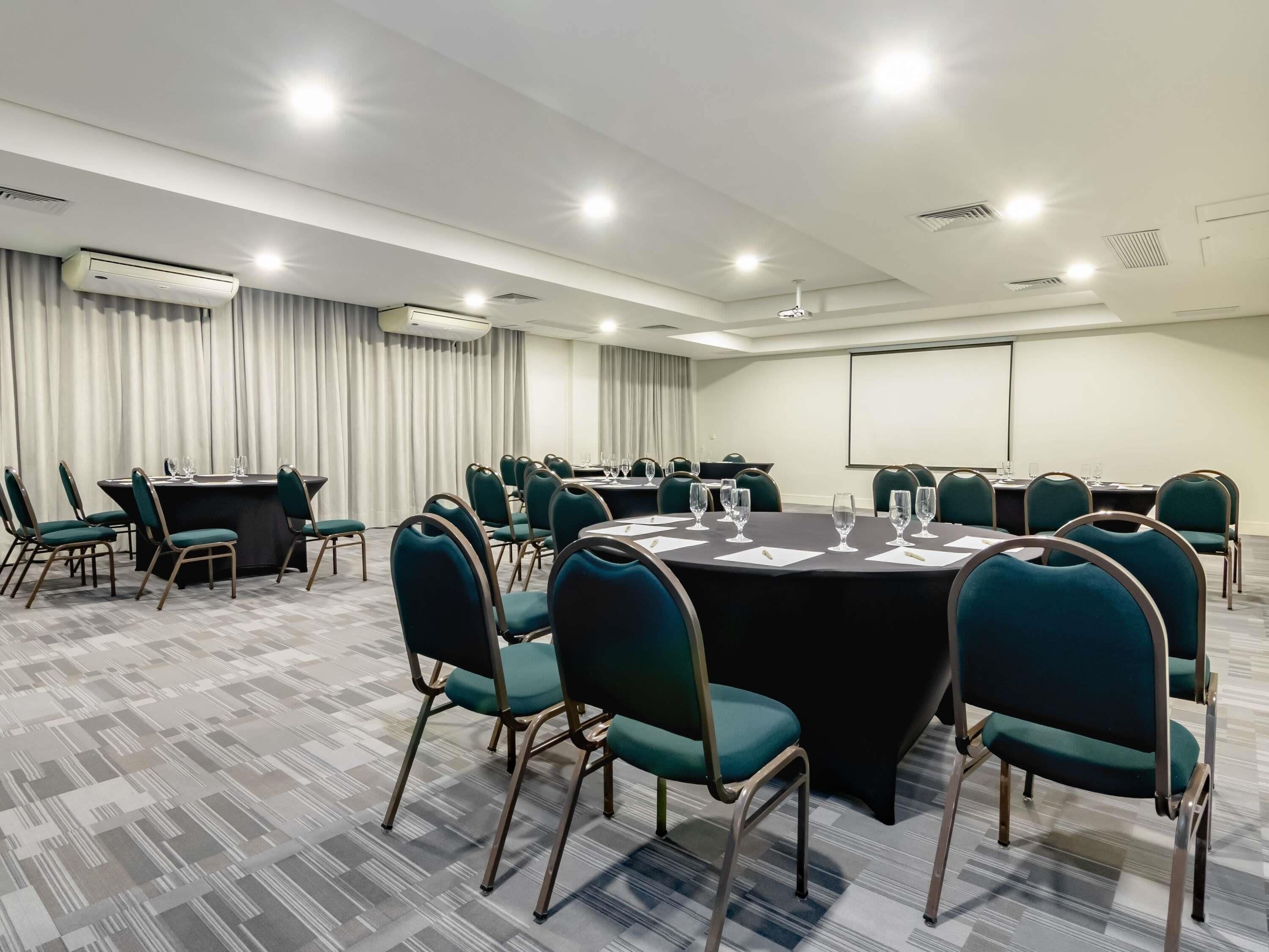 A conference room with a large table, chairs, and a projector screen.