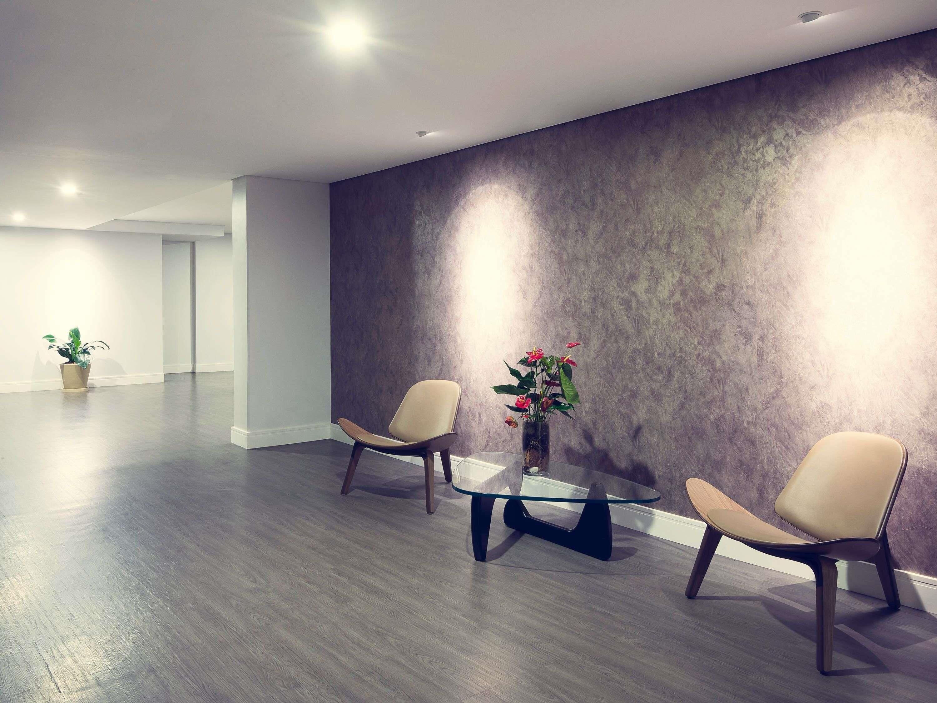 Una habitación moderna con dos sillas, una mesa de vidrio y una planta en maceta.