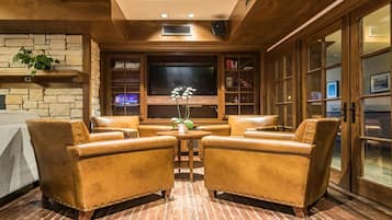 Eine gemütliche Lounge mit Ledersesseln, einem Flachbildfernseher und einem Bücherregal.