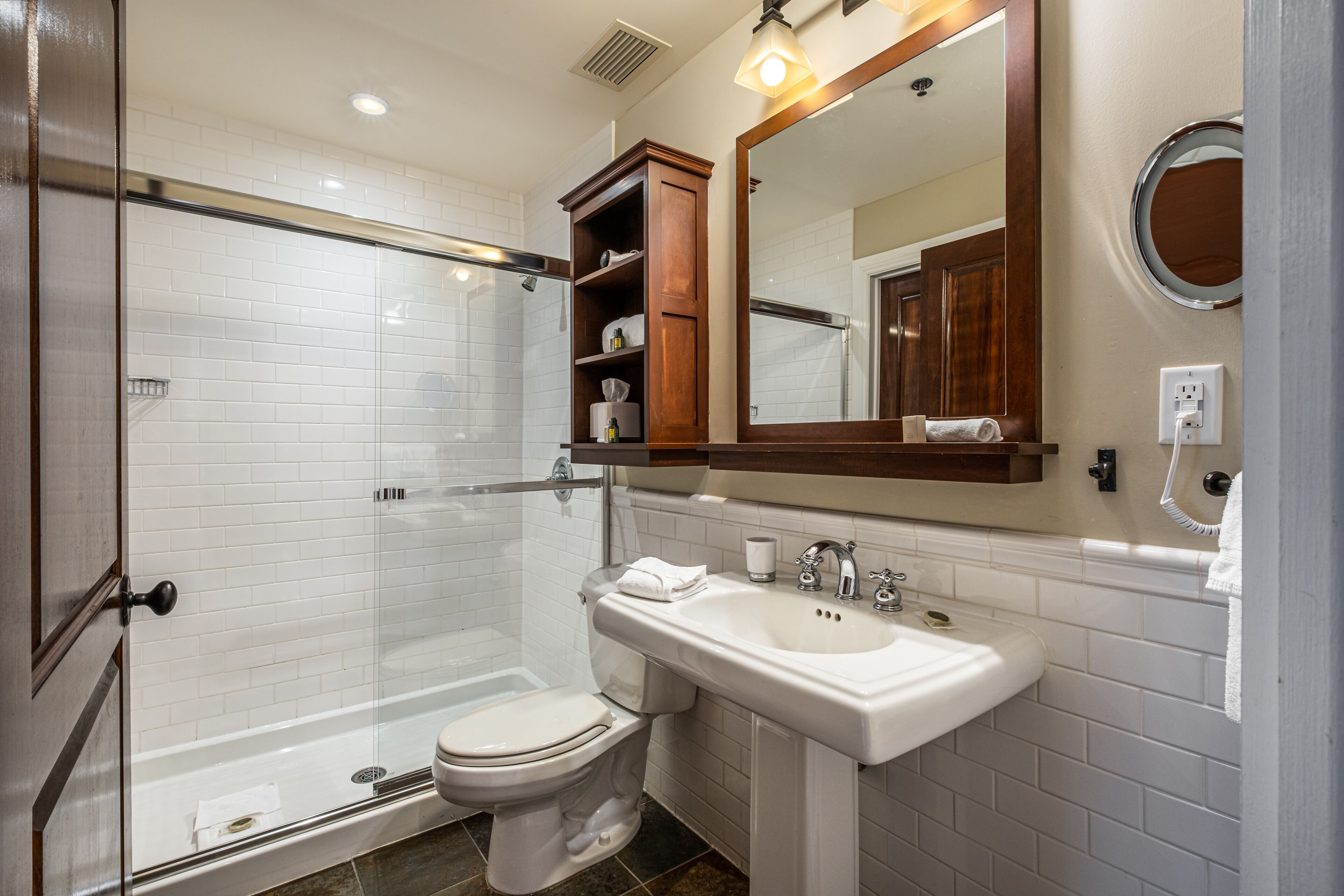 A modern bathroom with a glass-enclosed shower, a white sink, and a large mirror.