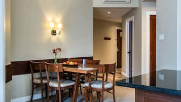 A dining area with a wooden table and chairs, a vase with flowers, and wall-mounted lighting.