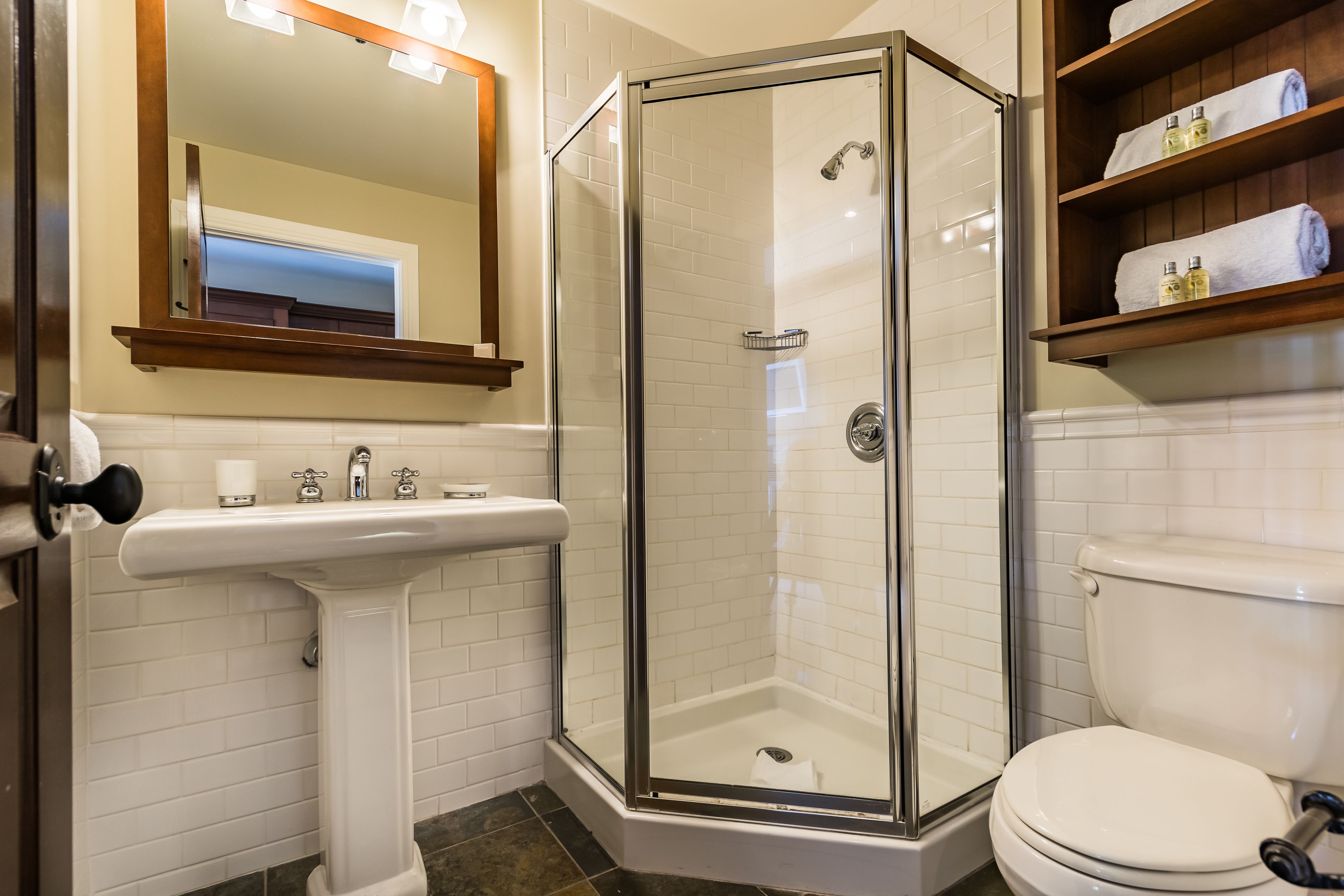 A bathroom with a glass-enclosed shower, a pedestal sink, and a toilet.