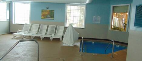 A swimming pool area with lounge chairs and a covered seating area.