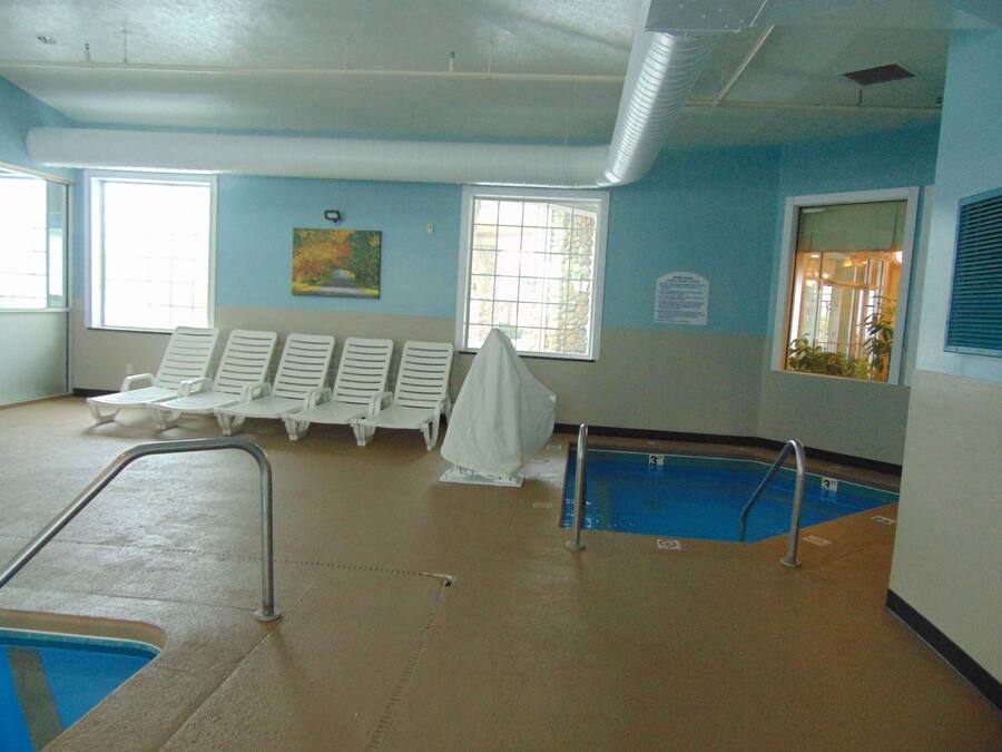 A swimming pool area with lounge chairs and a covered seating area.