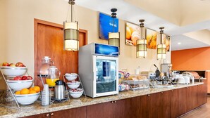 A hotel breakfast bar with a coffee machine, fruit bowls, and a refrigerator. - Comfort Suites Clovis - Fresno (Clovis)