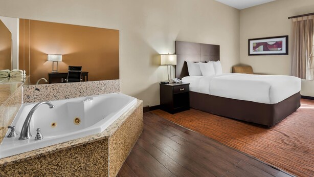 A hotel room with a large bed, a bathroom with a bathtub, a desk, and a chair. - Comfort Suites Clovis - Fresno (Clovis)