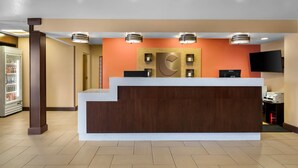A reception desk with a modern design, a refrigerator with beverages, and a flat-screen TV. - Comfort Suites Clovis - Fresno (Clovis)