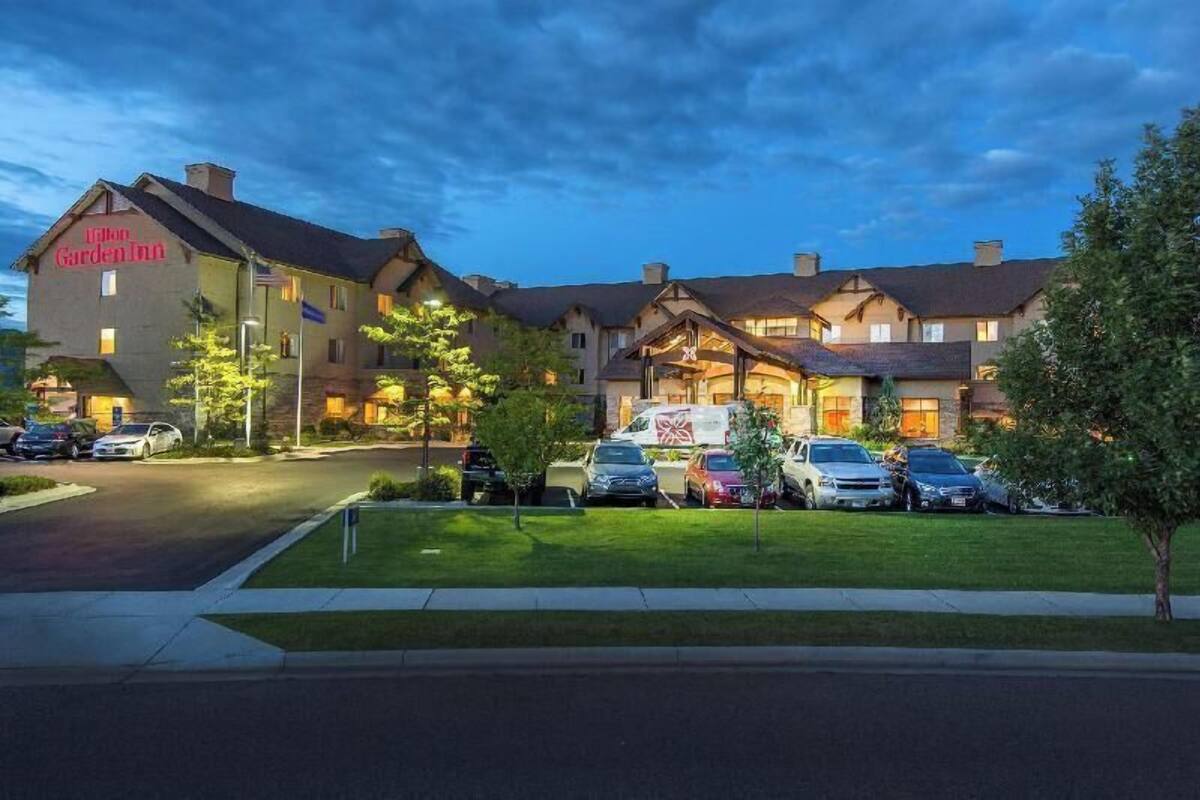 A hotel with a traditional architectural style, a parking lot, and a well-maintained lawn.