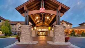 A hotel entrance with a covered walkway, stone pillars, and a sign with a leaf symbol. - Hilton Garden Inn Bozeman (Bozeman)