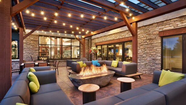 An outdoor patio with a fire pit, seating, and a stone wall. - Hilton Garden Inn Bozeman (Bozeman)