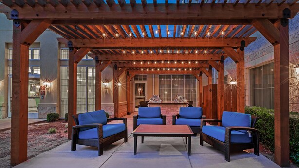 A covered patio area with wicker furniture and a brick fireplace. - Homewood Suites by Hilton Wichita Falls (Wichita Falls)