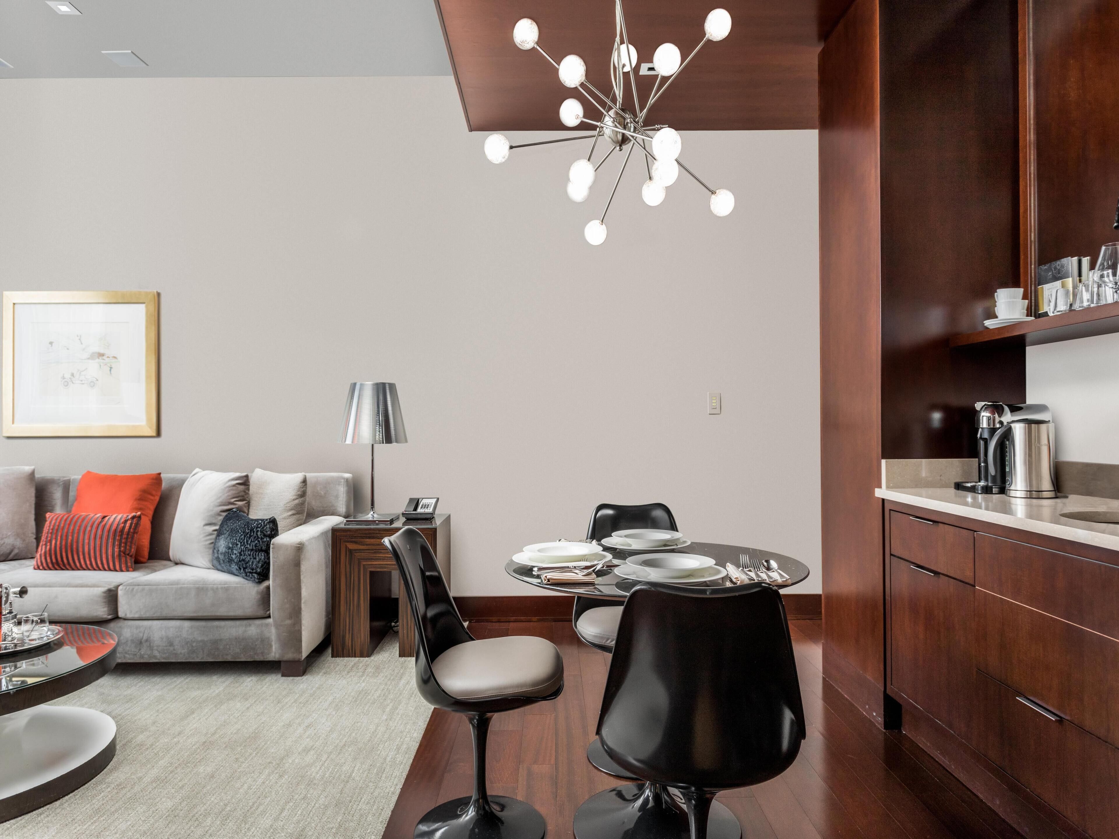 A modern living room with a sofa, coffee table, and dining area with chairs and a table set for two.
