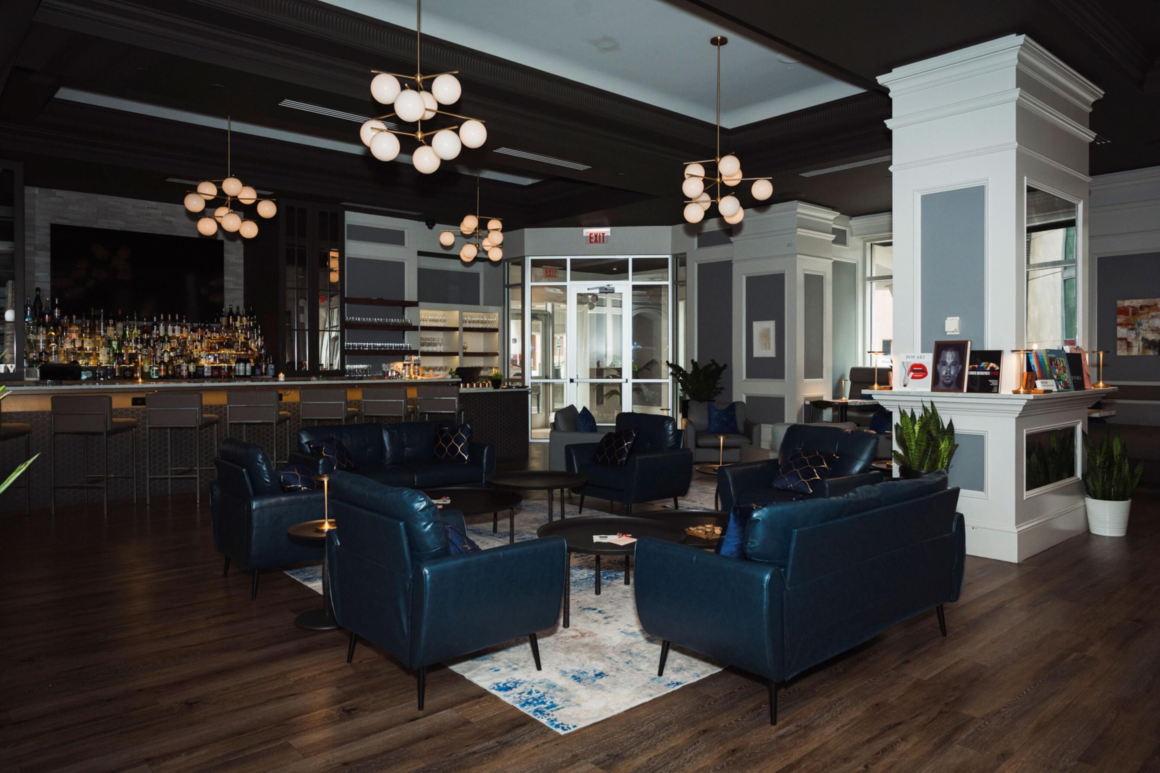 A modern bar area with a bar counter, seating with sofas, and hanging spherical light fixtures.