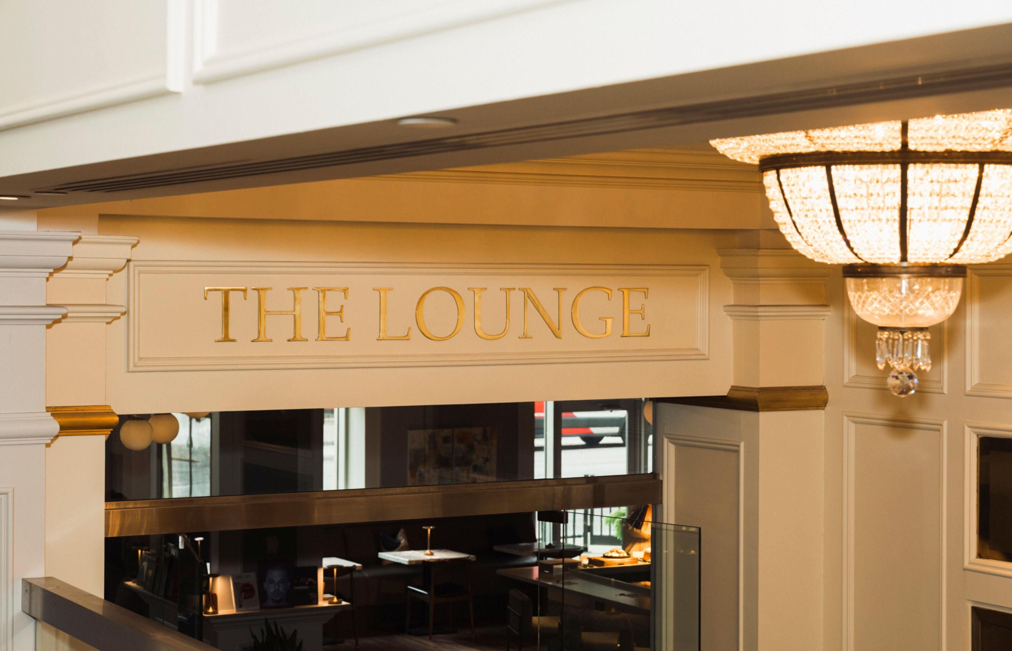 A sign reading 'THE LOUNGE' above a bar area with tables and chairs.