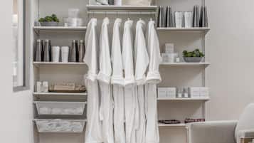 Un baño moderno con estantes blancos, zona de ducha y suelo de madera.