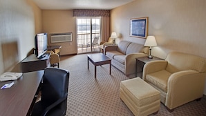 A hotel room with a desk, television, two chairs, a sofa, a lamp, and a window with a view. - Holiday Inn Express Le Claire Riverfront-Davenport by IHG (Le Claire)