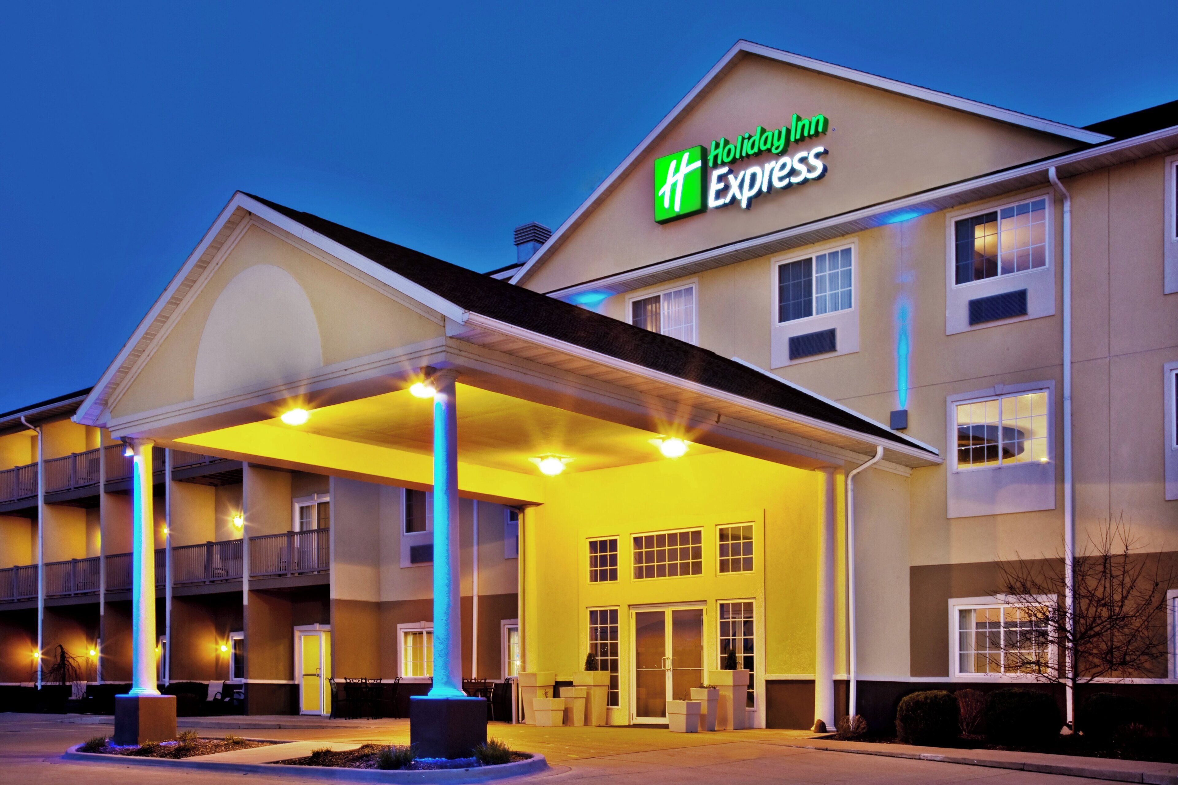 Ein Holiday Inn Express Hotel mit überdachter Eingangspartie, zahlreichen Fenstern und einer gut beleuchteten Fassade.