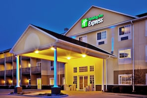 Un hotel Holiday Inn Express con una entrada cubierta, varias ventanas y una fachada bien iluminada.