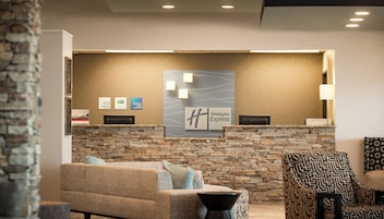 Una zona de recepción con pared de piedra, un cartel de Holiday Inn Express y un mostrador de recepción.