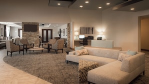 A spacious lobby with a reception desk, seating area with patterned chairs, and a large sectional sofa.