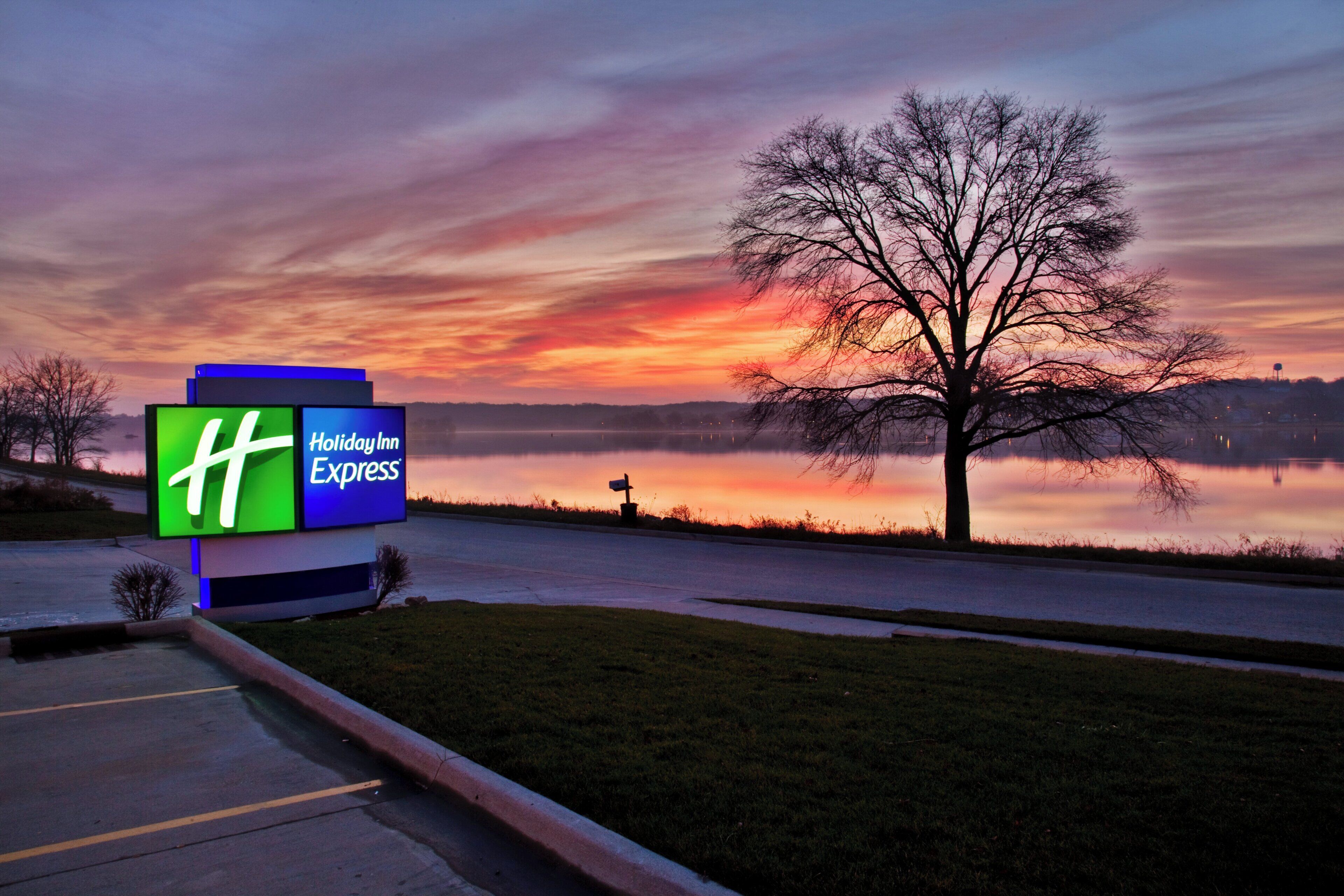 A Holiday Inn Express sign with a view of a lake and a sunset.