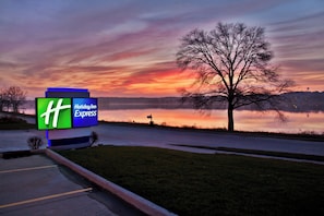 Señal de Holiday Inn Express con vistas a un lago y un atardecer.