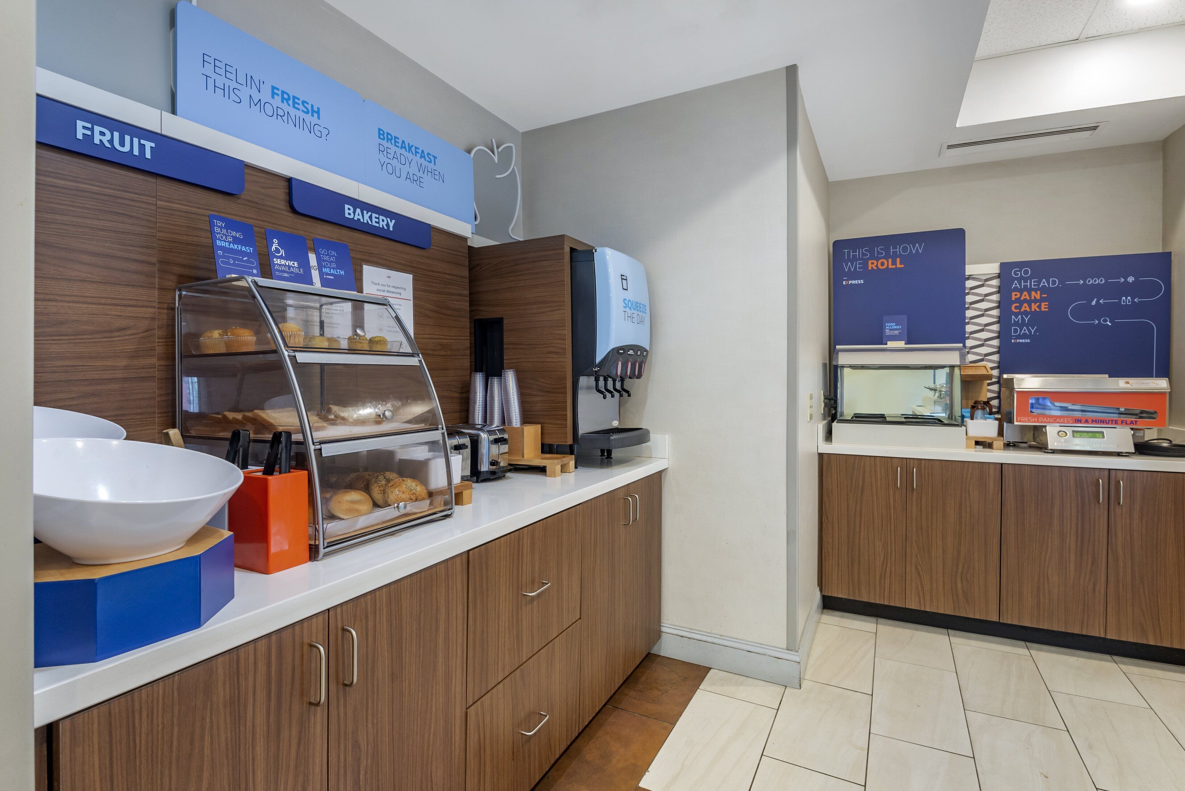 A modern kitchen area with a fruit display, bakery section, and a coffee machine.