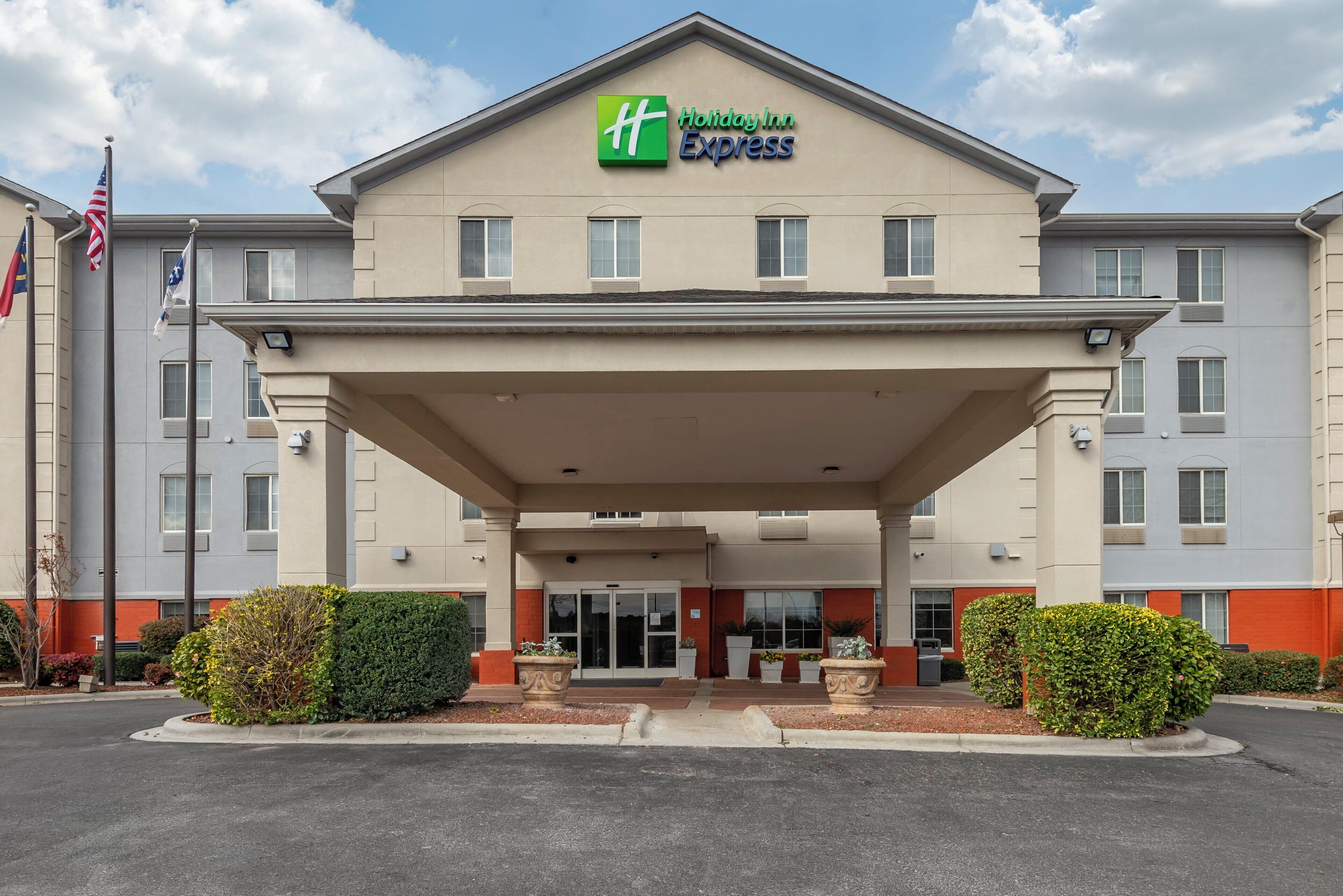 A Holiday Inn Express building with a covered entrance, multiple windows, and a flagpole with flags.