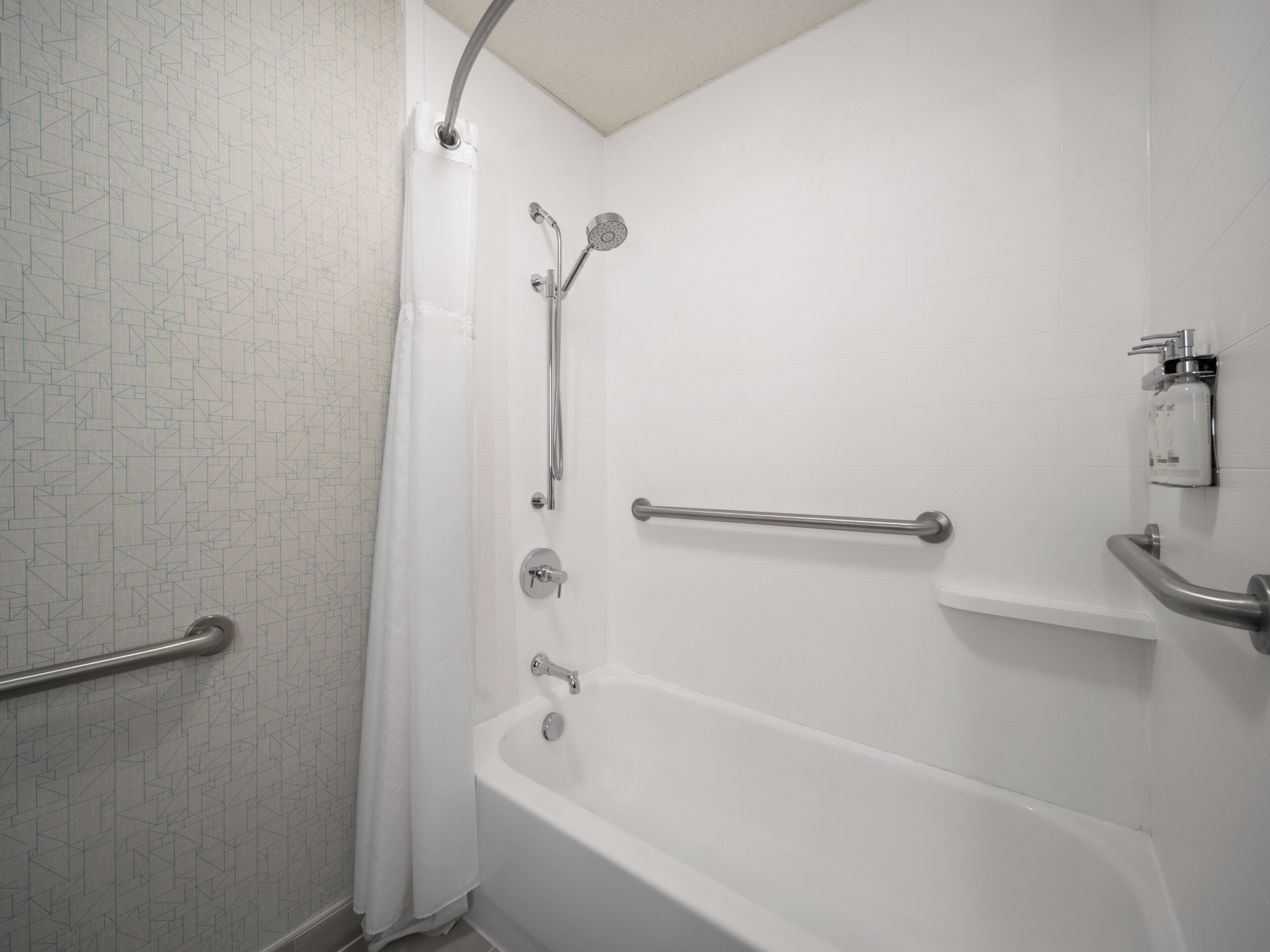 A bathroom with a shower, a bathtub, and a handrail.