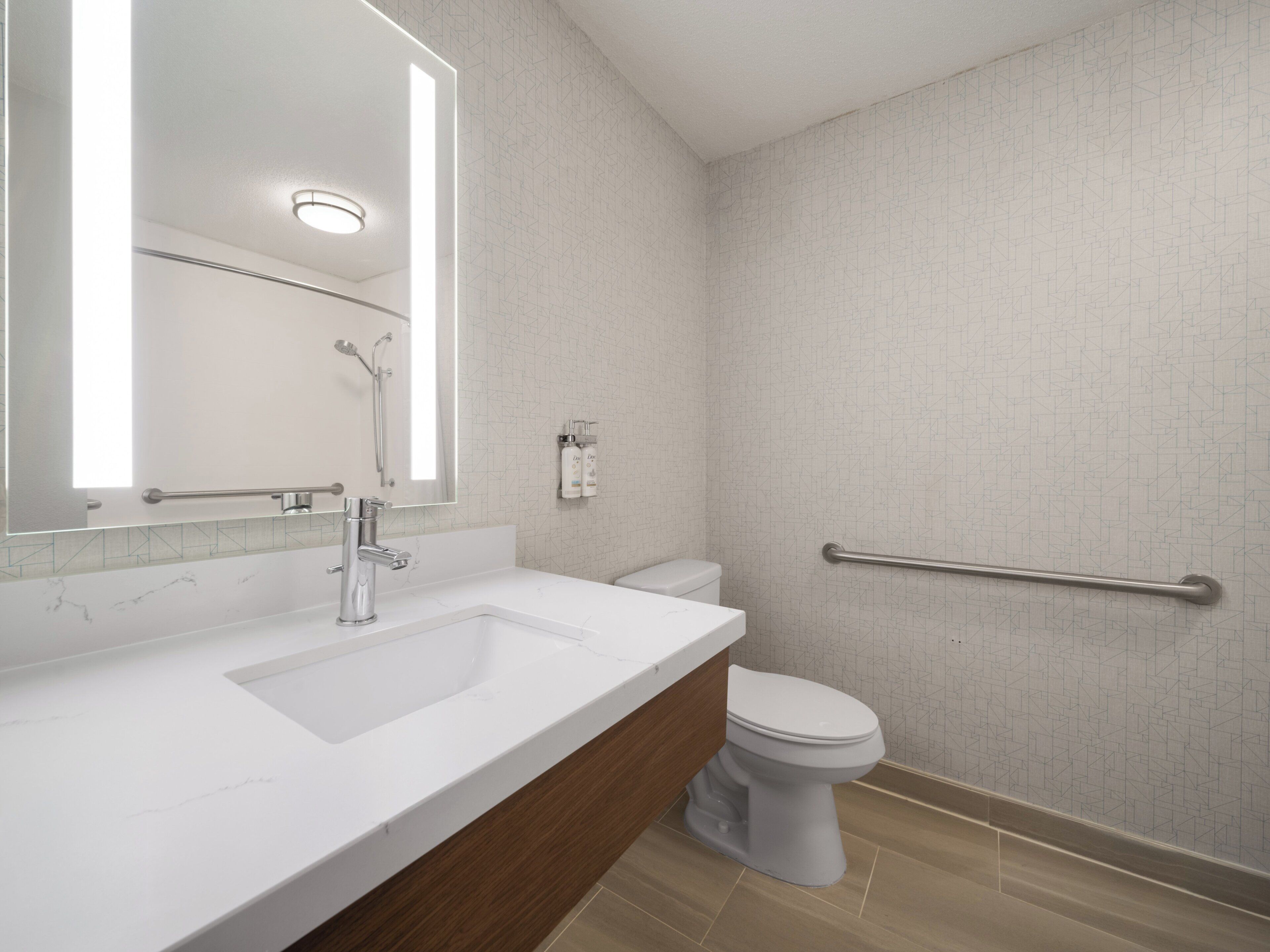 Un baño moderno con un lavabo blanco, un espejo, un inodoro y una zona de ducha.