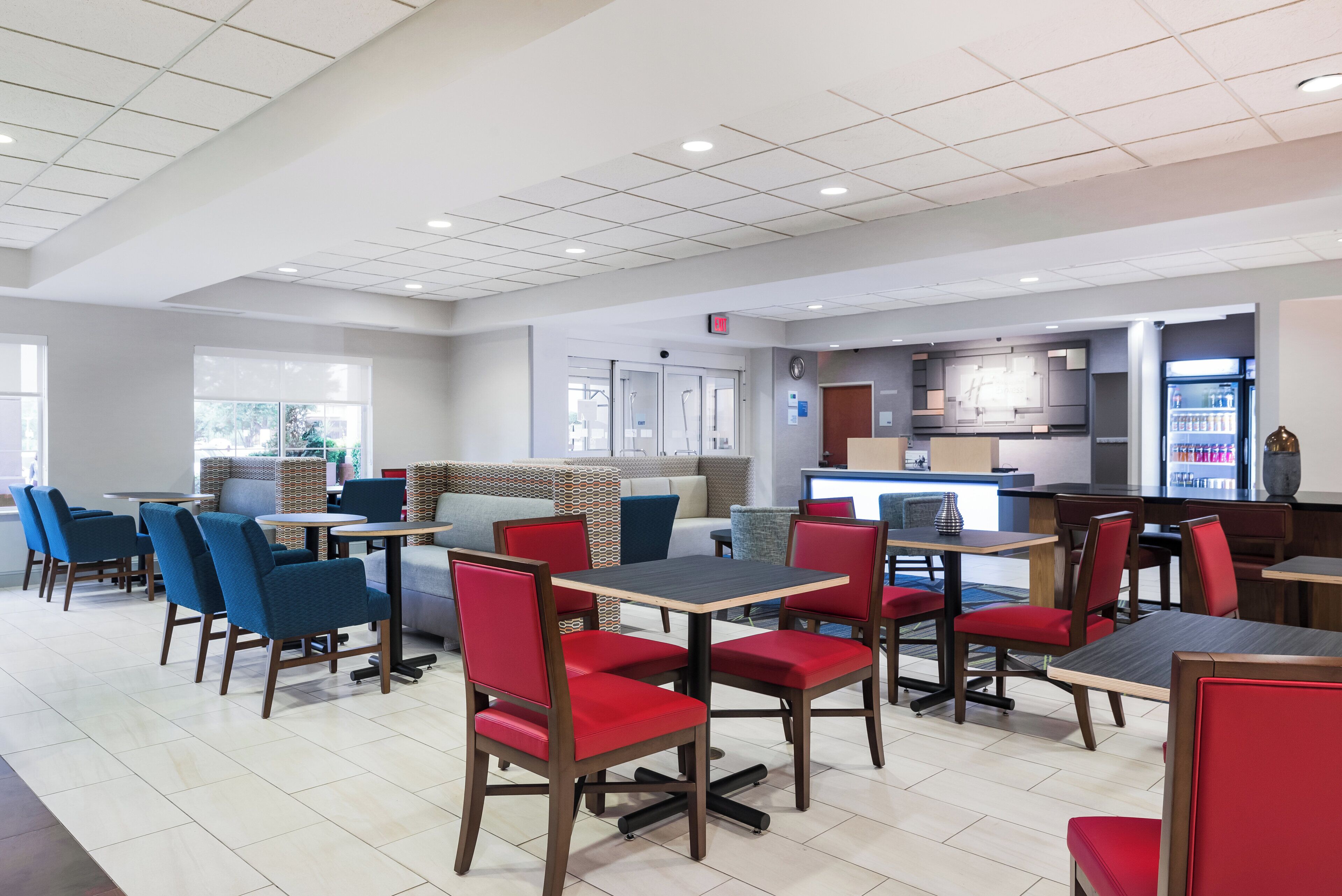 A modern restaurant with high tables and chairs, a bar area, and a visible exit sign.
