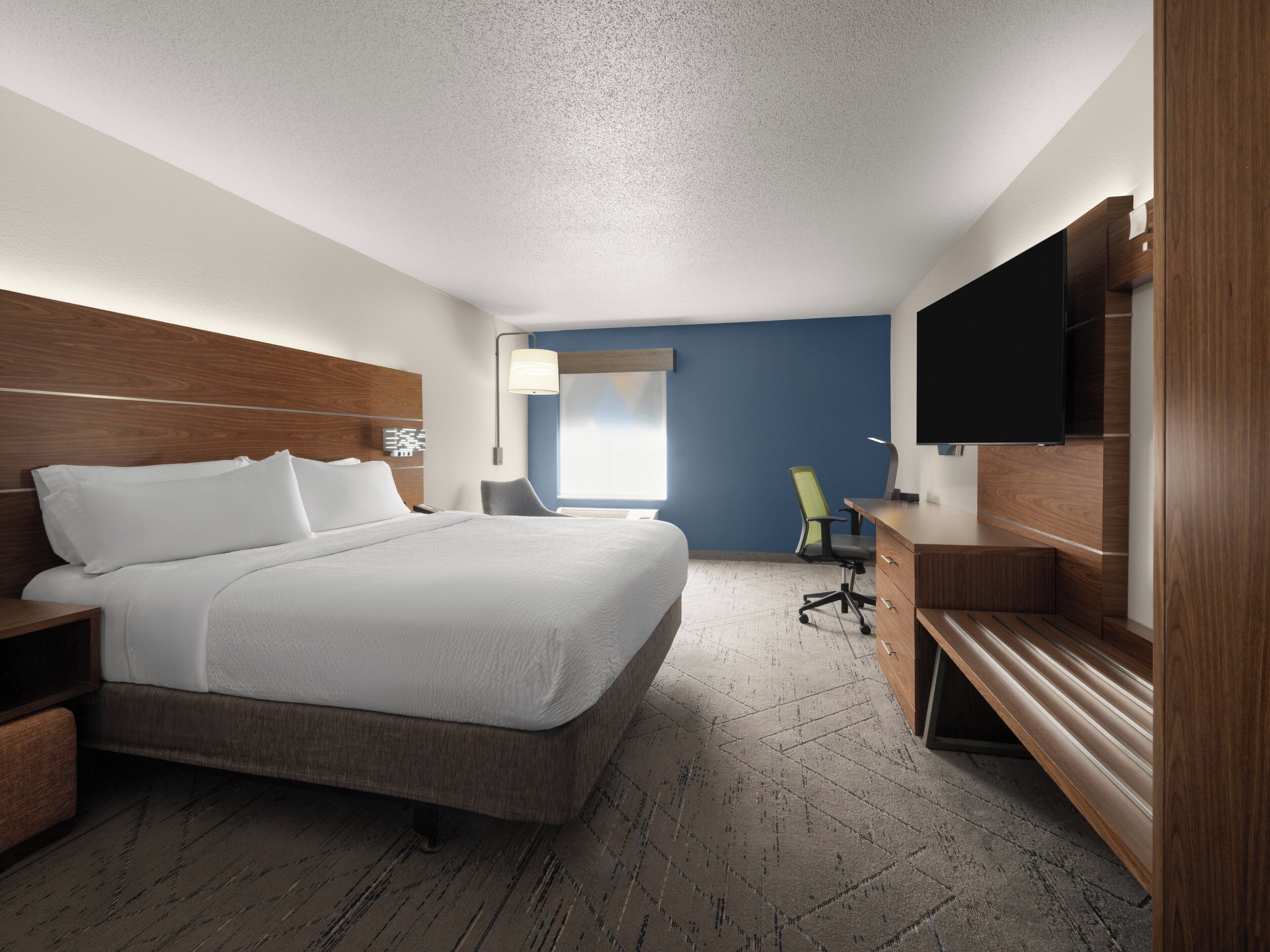 Una habitación de hotel con una cama grande, un escritorio, una silla, un televisor y una ventana.