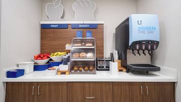Un buffet pour le petit-déjeuner proposant des fruits, des viennoiseries, une machine à café et un saladier de produits frais.