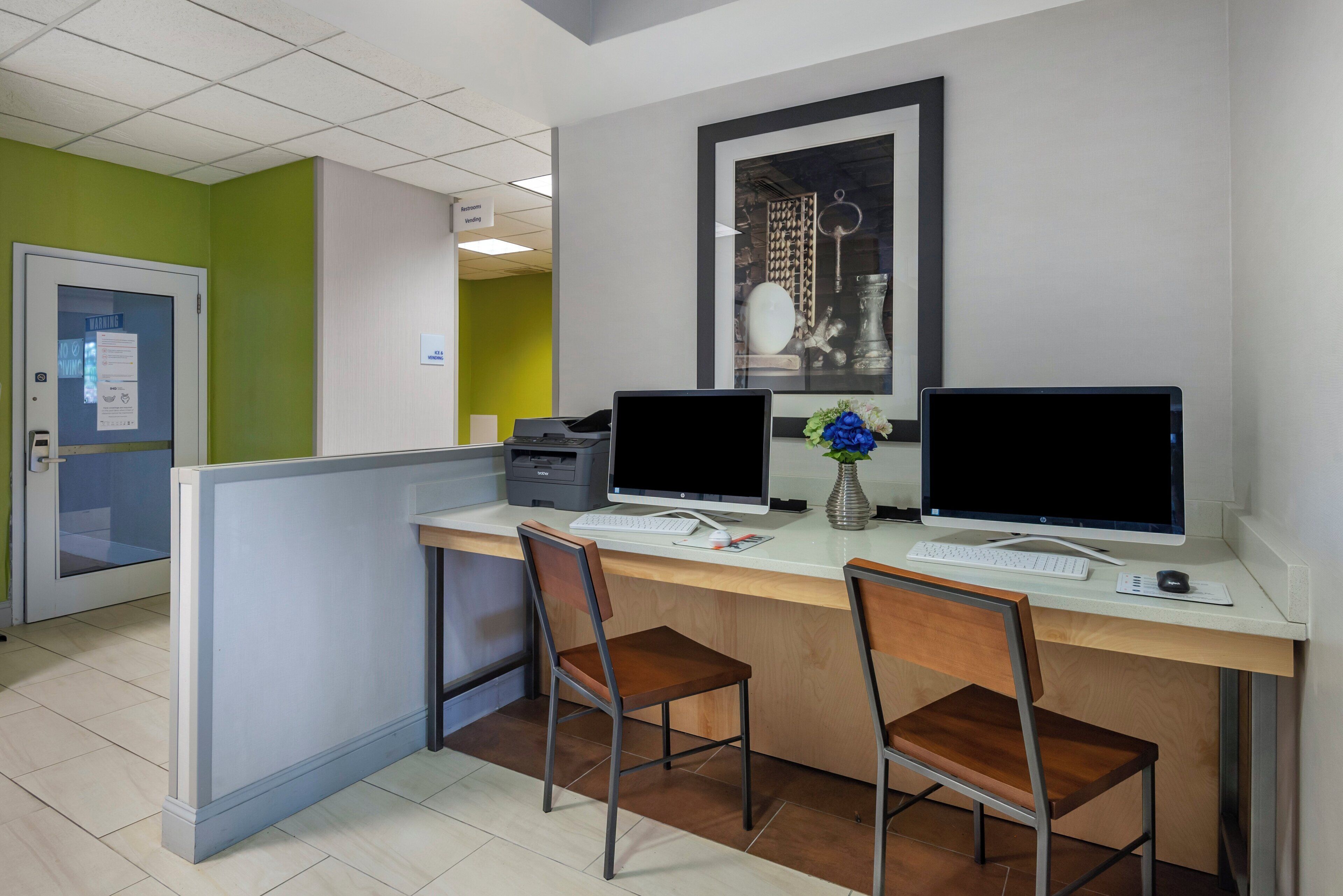 A reception desk with two computer monitors, a keyboard, and a mouse. There are two chairs in front of the desk.