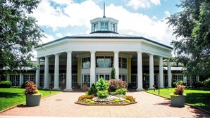 A large building with a central entrance flanked by columns, surrounded by a landscaped garden. - Holiday Inn Express Charlotte West - Gastonia by IHG. (Gastonia)