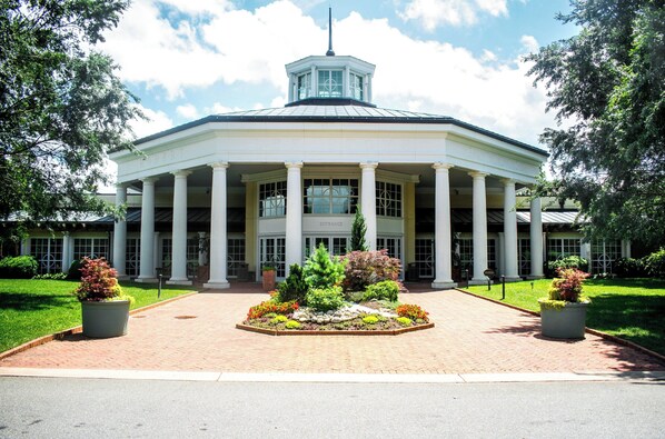 A large building with a central entrance flanked by columns, surrounded by a landscaped garden.