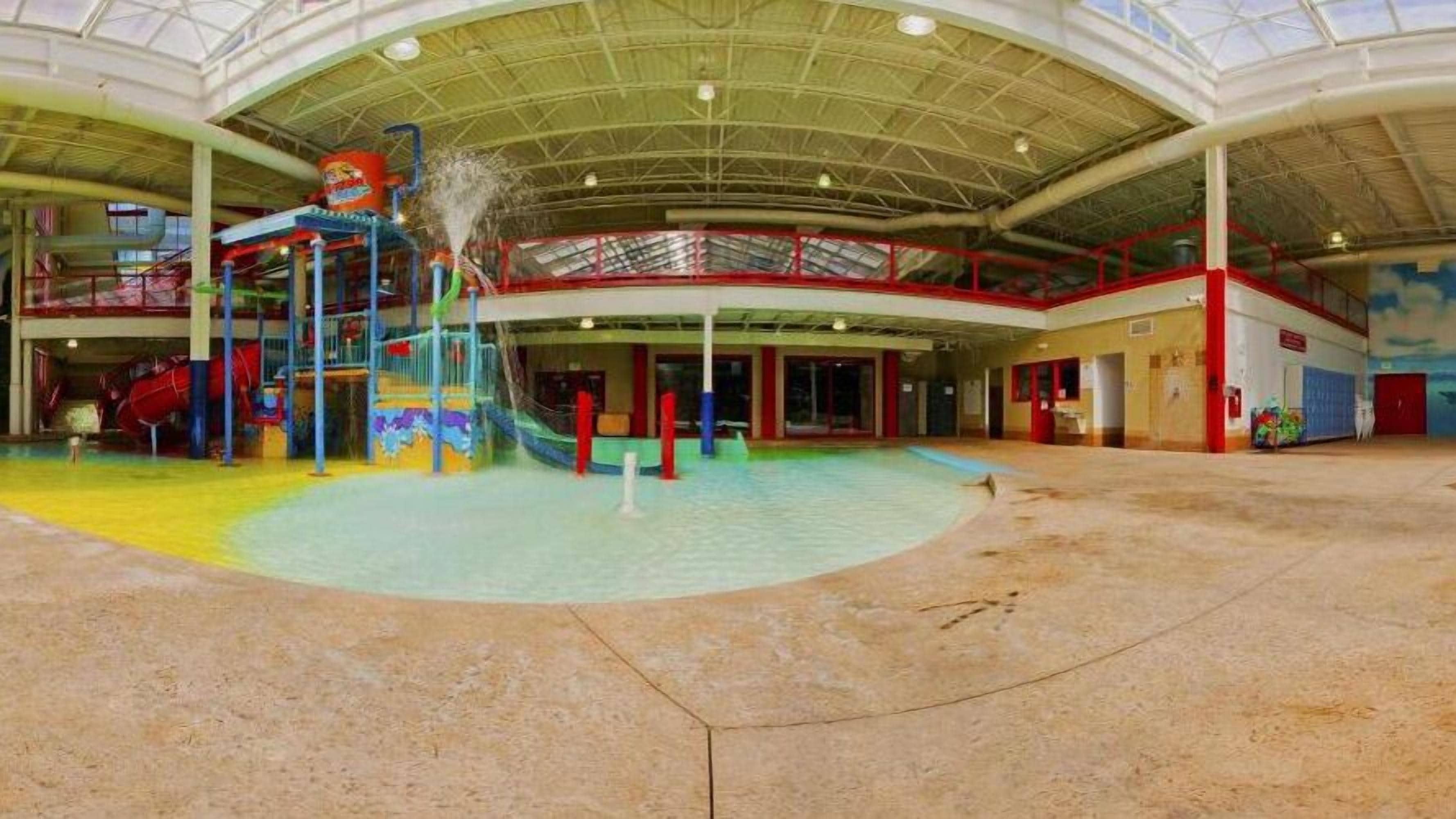 An indoor water park with a large pool, slides, and play structures.