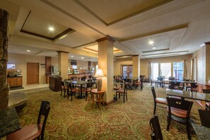 A spacious hotel lobby with multiple dining areas, a reception desk, and a buffet. - Triple Play Resort Hotel & Suites (Hayden)