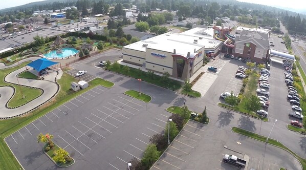 An aerial view of a parking lot with a large building labeled "TRIPLEPLAY" in the center, surrounded by greenery and a swimming pool. - Triple Play Resort Hotel & Suites (Hayden)