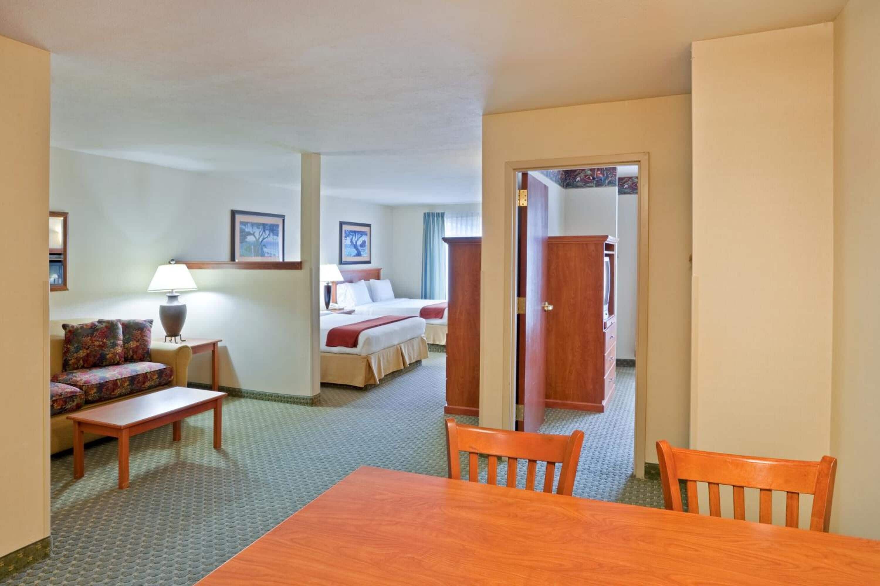 Una habitación de hotel con una cama, un sofá, una mesa de comedor y una silla.