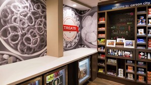 A snack bar with a 'TREATS' sign, refrigerated beverage dispensers, and shelves stocked with various snacks and sweets. - Hampton Inn & Suites Carson City (Carson City)
