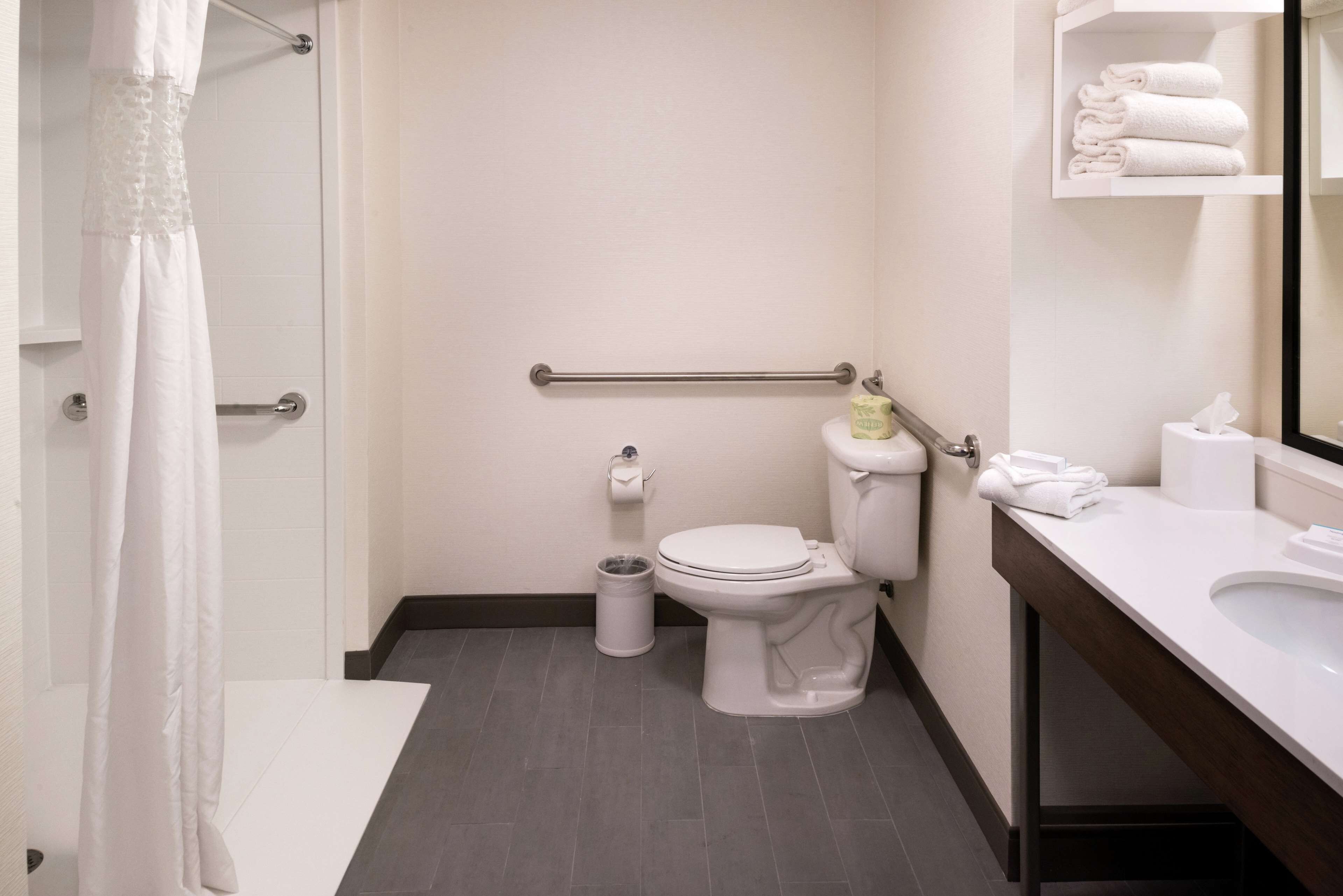 Een moderne badkamer met toilet, bidet en een wastafel met spiegel.