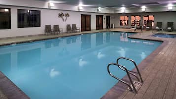 A large indoor swimming pool with clear water, surrounded by lounge chairs and a tiled deck.