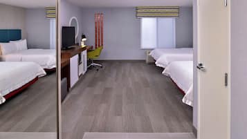 Ett hotellrum med två sängar, ett skrivbord med en stol, en TV och ett fönster med gardiner.